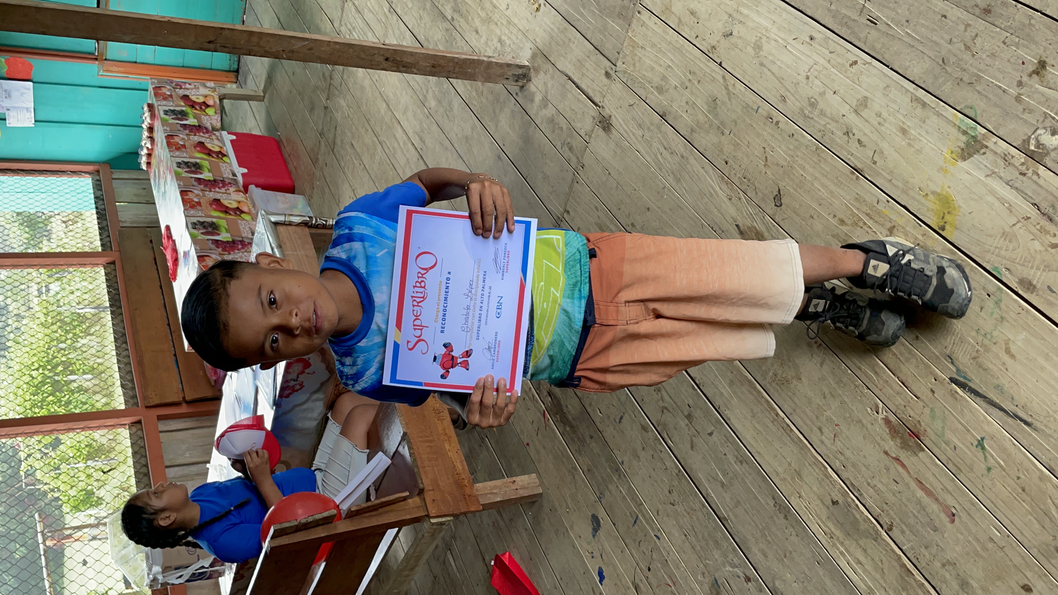 A young boy holds up a certificate declaring his faith in Jesus.