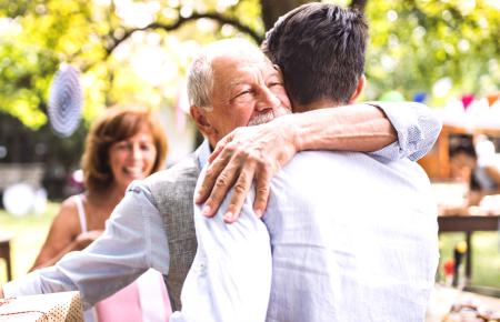 Elderly father hugging adult son