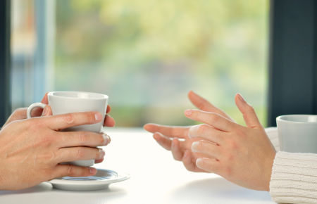 A man and a woman chatting at a table with cups of hot tea