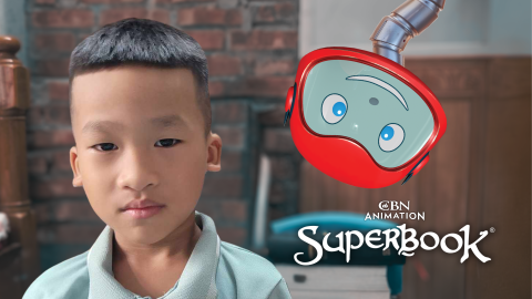 Thien Quoc, a 6-year-old boy from Vietnam, faces the camera. Gizmo's neck is extended and his head hangs down from above on the right of the picture. The CBN Animation and Superbook logos are stacked below Gizmo's head.