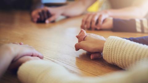 a group of friends holding hands and praying