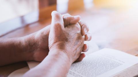 clasped hands on book