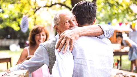 Elderly father hugging adult son
