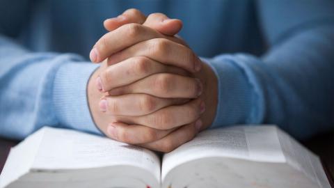 Hands folded on Bible