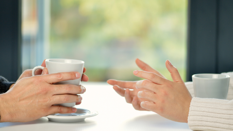 A man and a woman chatting at a table with cups of hot tea