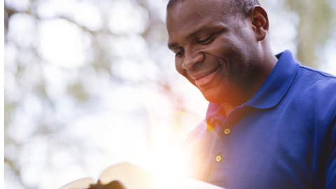  man reading the Bible outside with sun pouring in