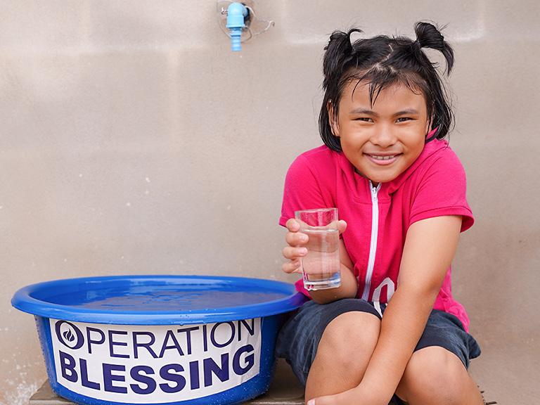Girl with water from CBN's Operation Blessing